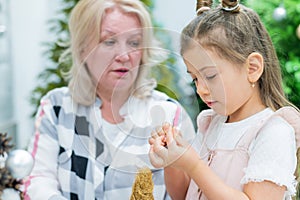 Elderly caucasian woman making pine cones decoration for christmas with two granddaughters