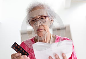 Elderly caucasian woman with medicine and reading drug prescript