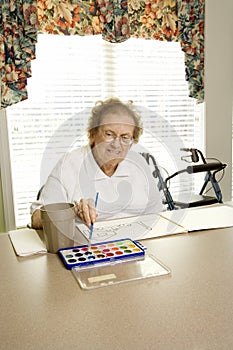 Elderly Caucasian woman painting with watercolors.