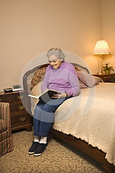 Elderly Caucasian woman reading book.