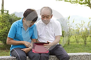 Elderly Chinese couple looking at the mobile tablet