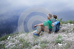 Elderly couple with backpacks sits on the mountain. photo