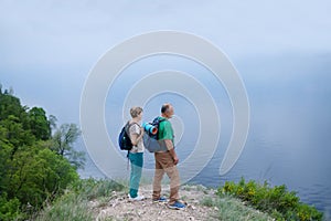 Elderly couple with backpacks travels around mountains.