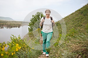 Elderly couple with backpacks travels around mountains.