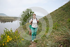 Elderly couple with backpacks travels around mountains.