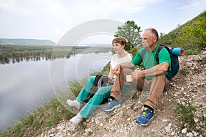 Elderly couple with backpacks travels around mountains.