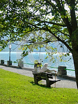 Elderly couple on a bench beside a mountain lake