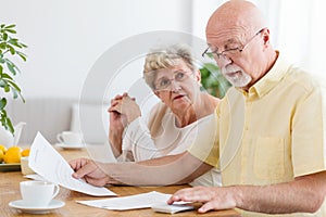 Elderly couple calculating costs of household. Senior people wit