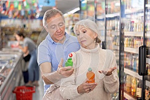 Elderly couple choosing sweet sodas together in the grocery section of supermarket