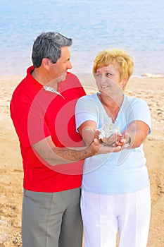 Elderly couple on the coast ,holding corals.