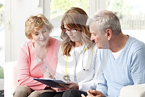 Elderly couple consulting with female doctor