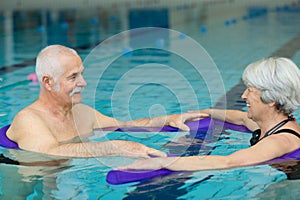 elderly couple doing exercise movement in swimming pool
