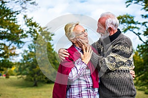 Elderly couple embracing in autumn park. Enjoying in love.