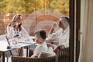 An elderly couple enjoys the terrace of a luxury house with their son during the holidays. Selective focus