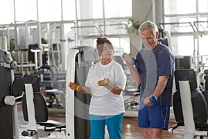 Elderly couple exercising at gym.