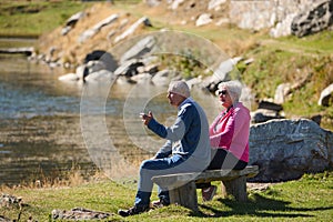 Elderly couple finding solace and joy as they rest on a park bench, engaged in heartfelt conversation, following a