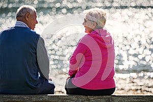 Elderly couple finding solace and joy as they rest on a park bench, engaged in heartfelt conversation, following a