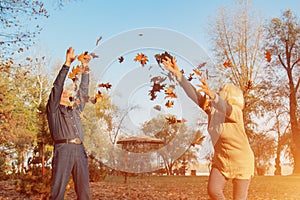 Elderly couple happily throws autumn fall leaves sitting in a park. Positive emotions of the elderly