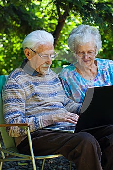 Elderly couple having fun with the laptop outdoors