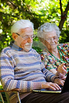 Elderly couple having fun with the laptop outdoors