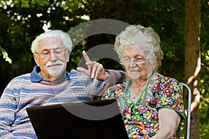 Elderly couple having fun with the laptop outdoors