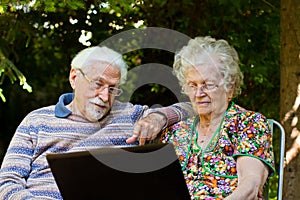 Elderly couple having fun with the laptop outdoors