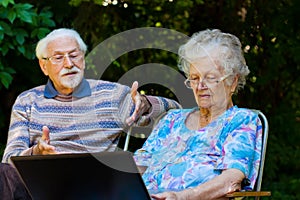 Elderly couple having fun with the laptop outdoors