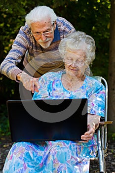 Elderly couple having fun with the laptop outdoors