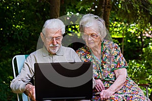 Elderly couple having fun with the laptop outdoors