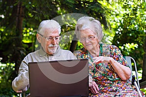 Elderly couple having fun with the laptop outdoors