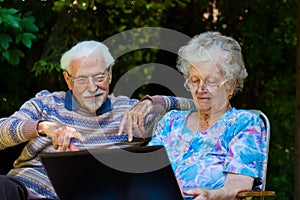 Elderly couple having fun with the laptop outdoors