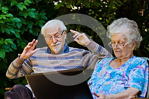 Elderly couple having fun with the laptop outdoors