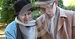 Elderly couple having positive emotions, talking when looking family photo album