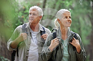 Elderly couple, hiking and active seniors in a forest, happy and relax while walking in nature. Senior, backpacker and