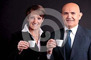 An elderly couple holding up two cups of espreso coffee