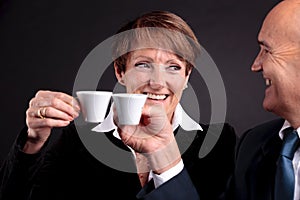 An elderly couple holding up two cups of espreso coffee