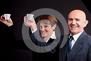 An elderly couple holding up two cups of espreso coffee photo
