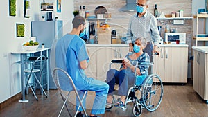 Elderly couple home visit by geriatrician in protective wear photo