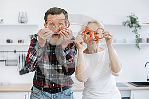 Elderly couple, husband and wife, having fun in kitchen while preparing breakfast.