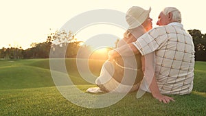 Elderly couple kissing on green grass.