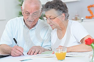 Elderly couple looking at magazine and taking notes