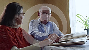 Elderly couple in love enjoy moments of family life looking through old photos from a photo album