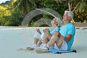 Elderly couple meditate on beach