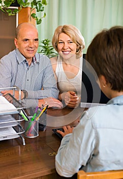 Elderly couple of pensioners talking with employee