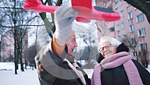 Elderly couple planing winter holidays. Man flying toy airplane
