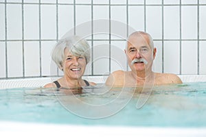 elderly couple posing in swimming pool