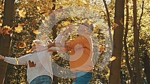 Elderly couple relaxing in nature. throwing yellow leaves in the air