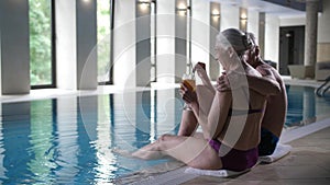 Elderly couple relaxing on side of swimming pool