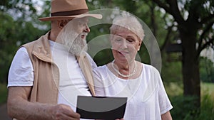 An elderly couple remembers joyful moments looking at a photograph in their hands. Happy couple talking and smiling