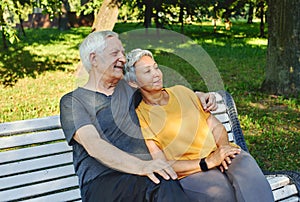 Elderly couple resting sit on bench in summer park